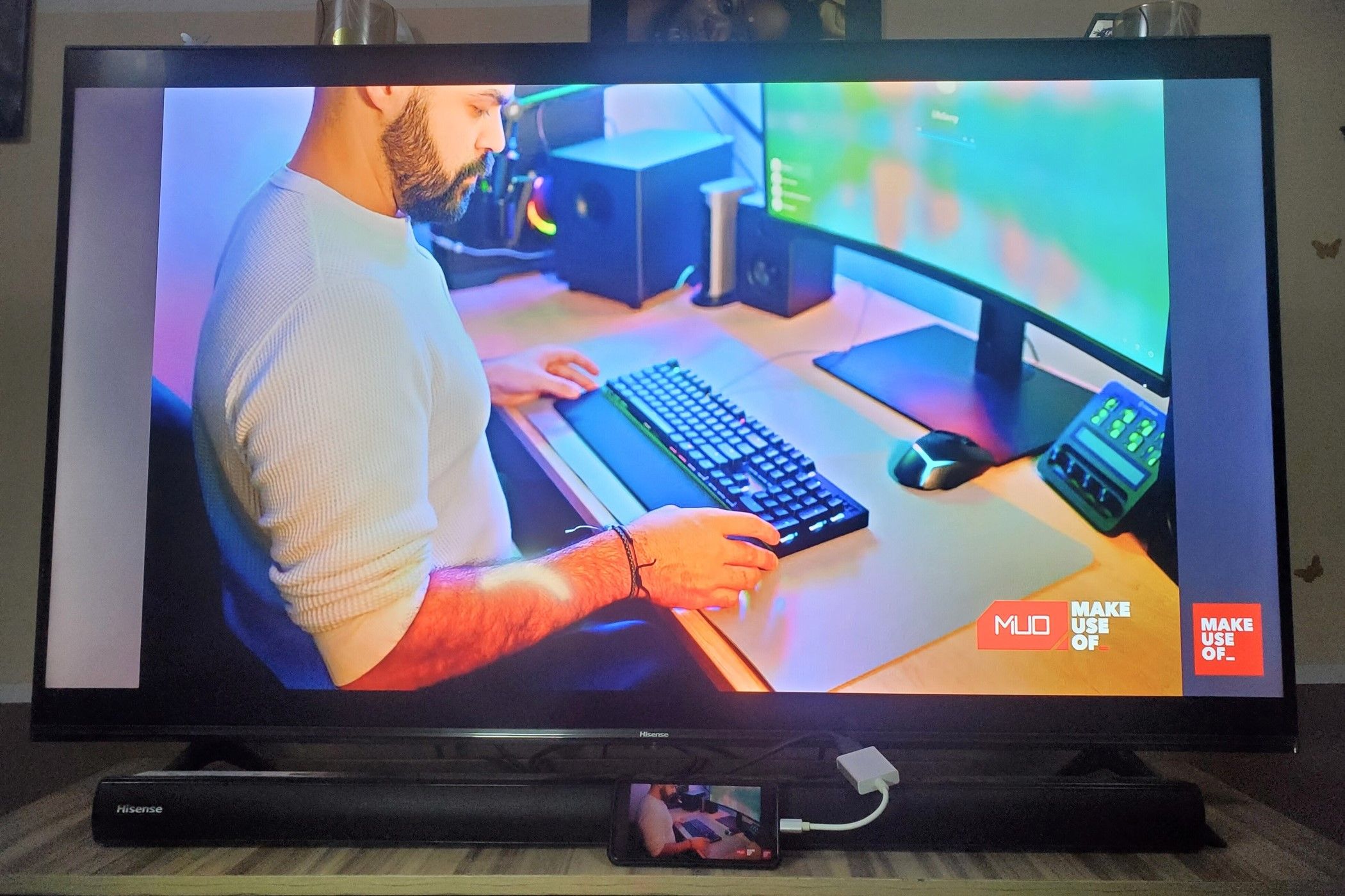 A smartphone connected to a TV via a USB-c to HDMI adapter mirroring it's screen and displaying a man using a keyboard-2