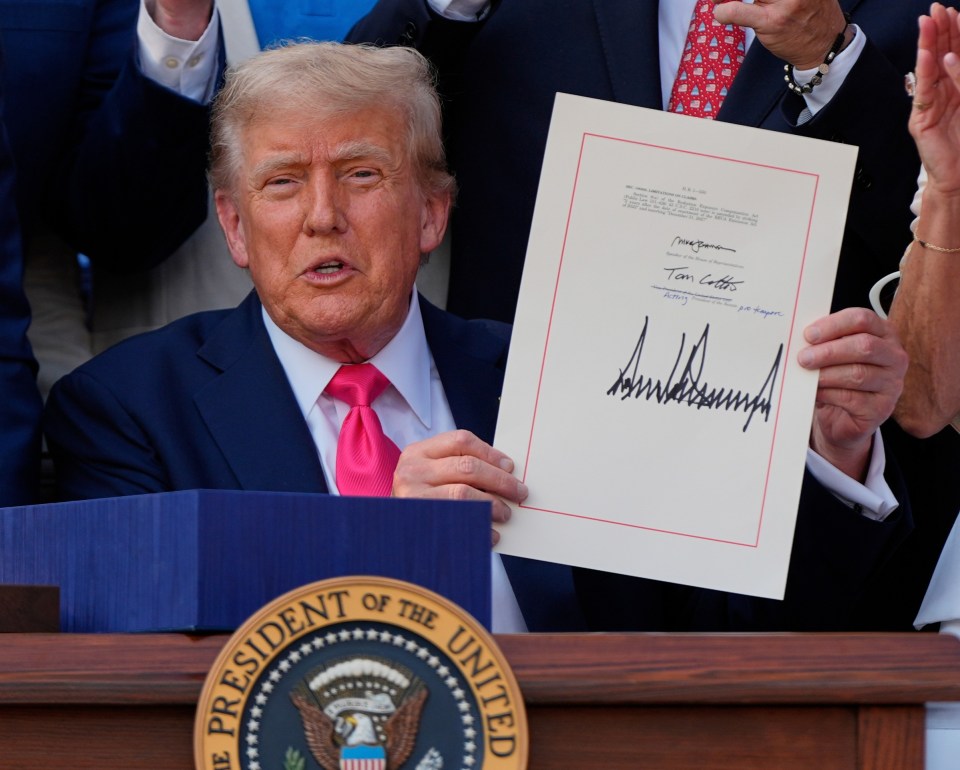 President Trump signing a bill surrounded by Congress members.