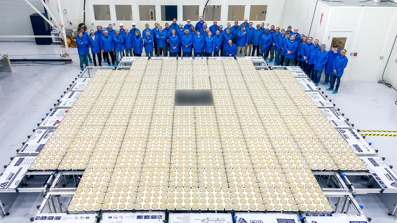 AST staff posing for a photo standing behind on the massive array of a BlueBird satellite