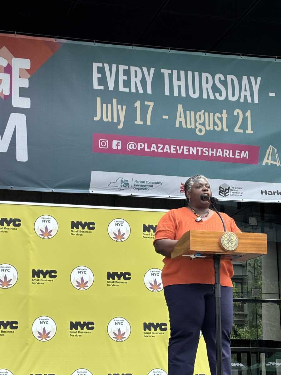 woman in orange shirt speaks at podium