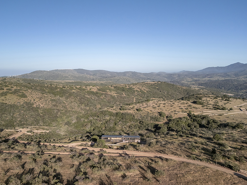 charred timber wraps linear casa las tupas, topped with pitched roof in northern chile