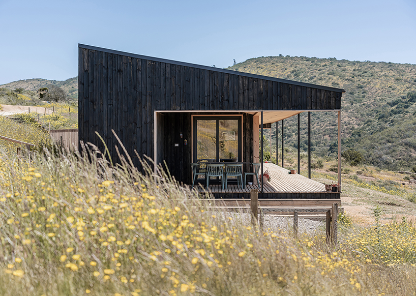 charred timber wraps linear casa las tupas, topped with pitched roof in northern chile