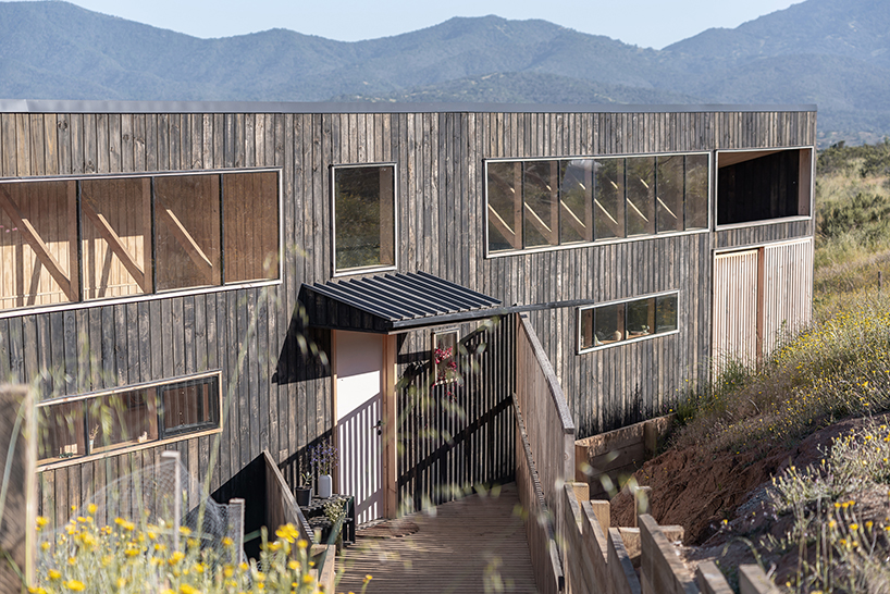 charred timber wraps linear casa las tupas, topped with pitched roof in northern chile
