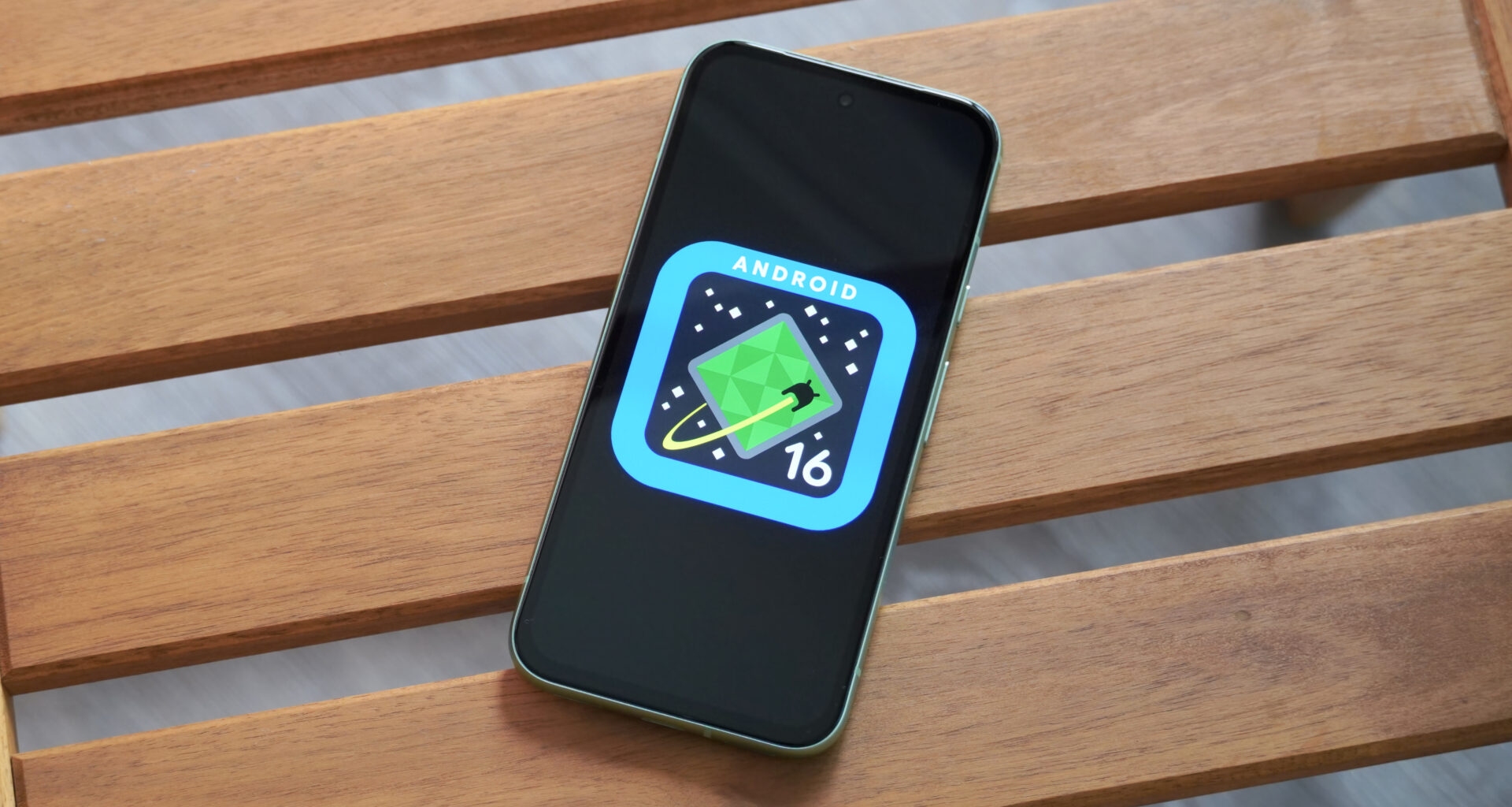 The Android 16 logo on a Google Pixel 8a outdoors.