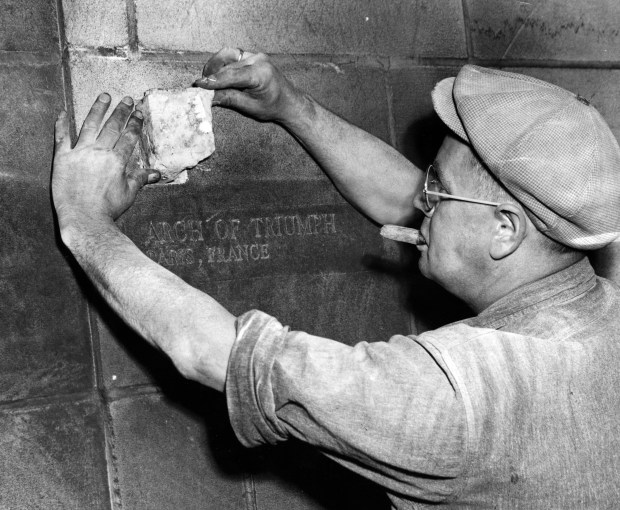 Henry Gast sets a stone from the Arch of Triump in Paris, France into the wall of Tribune Tower in Nathan Hale Court on Sept. 16, 1953, in Chicago. (Thomas Johnson/Chicago Tribune) 
