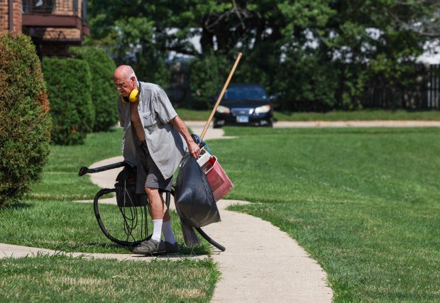 A maintenance worker lugs cleaning eqpuiment into an apartment building at the Elm Court Apartments on July 21, 2025, in Bensenville. The community has had numerous ICE raids over the last several months and dozens of people have been detained. (Stacey Wescott/Chicago Tribune)