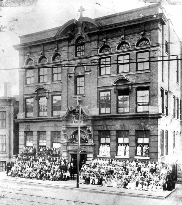 Children pose in windows and above the door at Assumption School in Chicago, circa 1900. (University of Illinois at Chicago Collections)