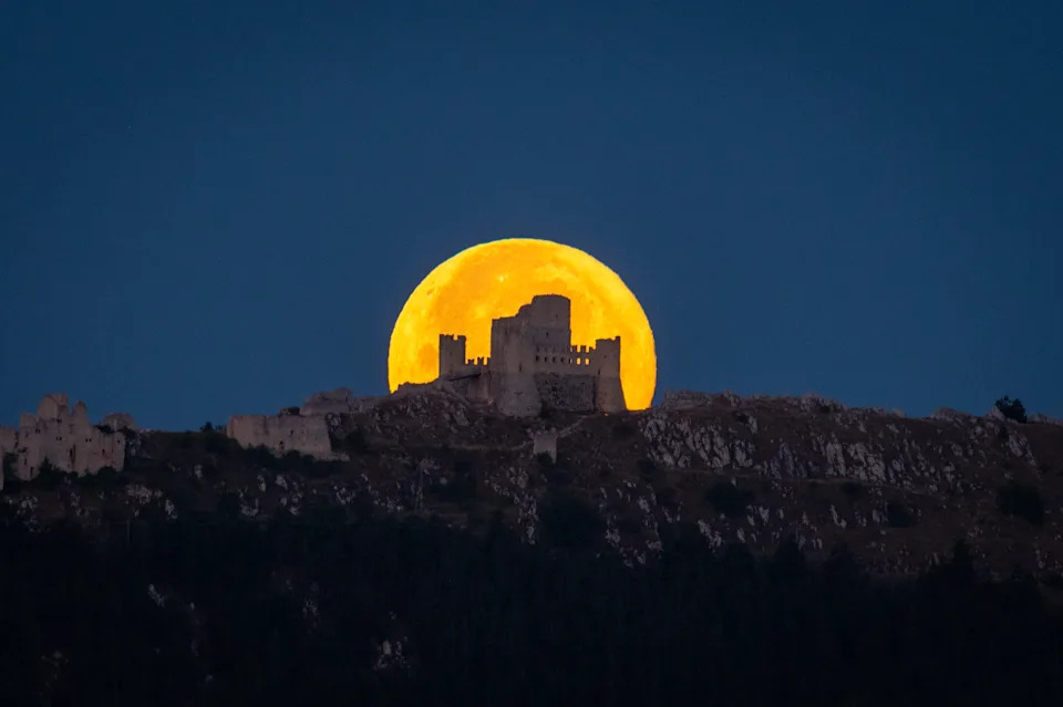 The full moon sets behind the Rocca Calascio castle in Italy. 