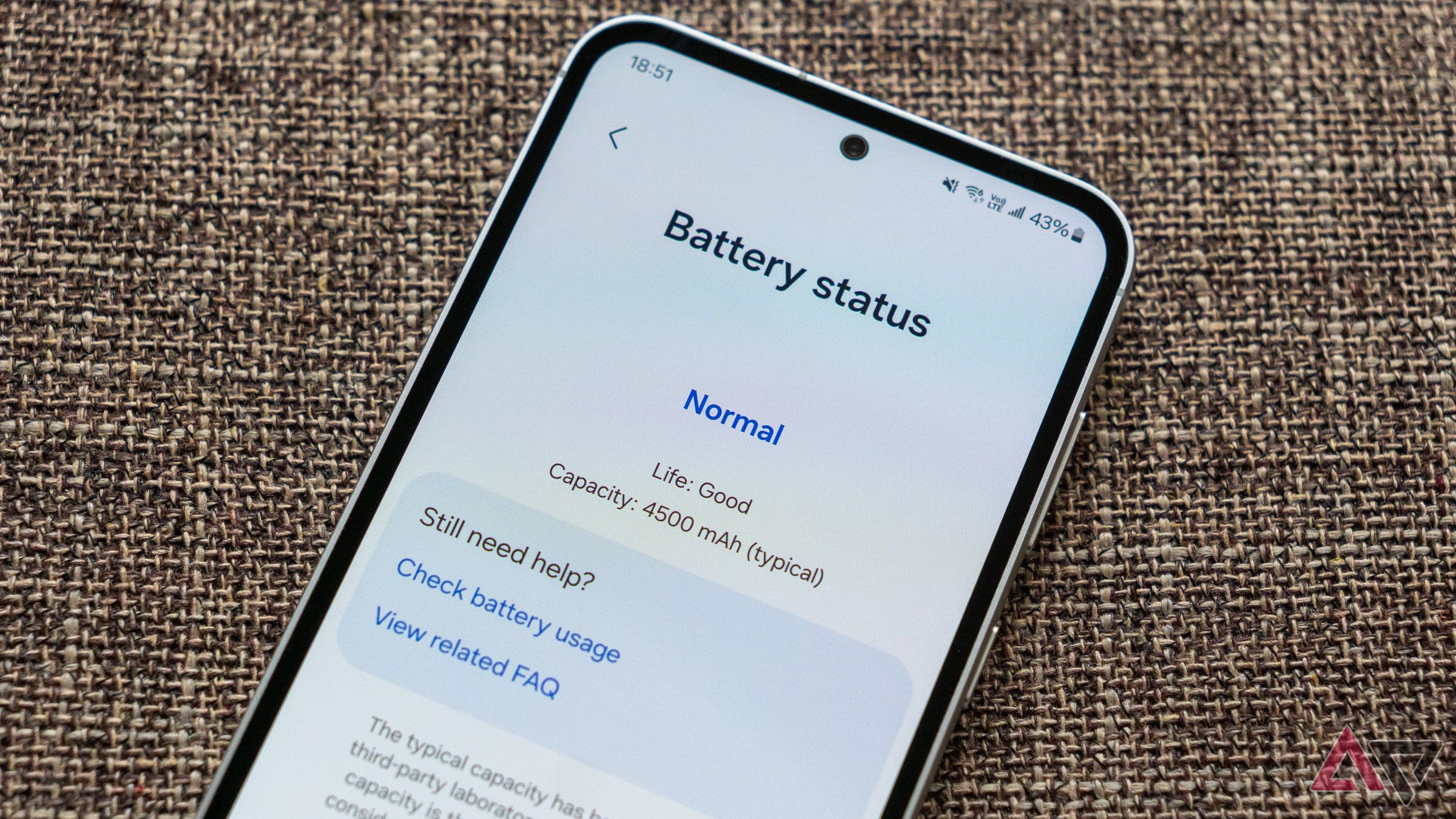 a phone on a fabric surface displaying the battery health info screen in the samsung members app
