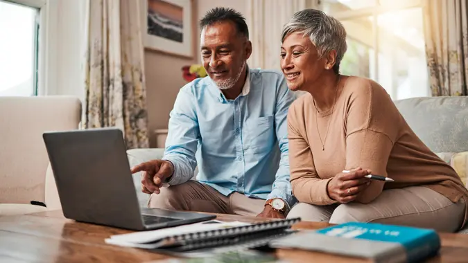 Mature couple on sofa using a laptop for planning finances.