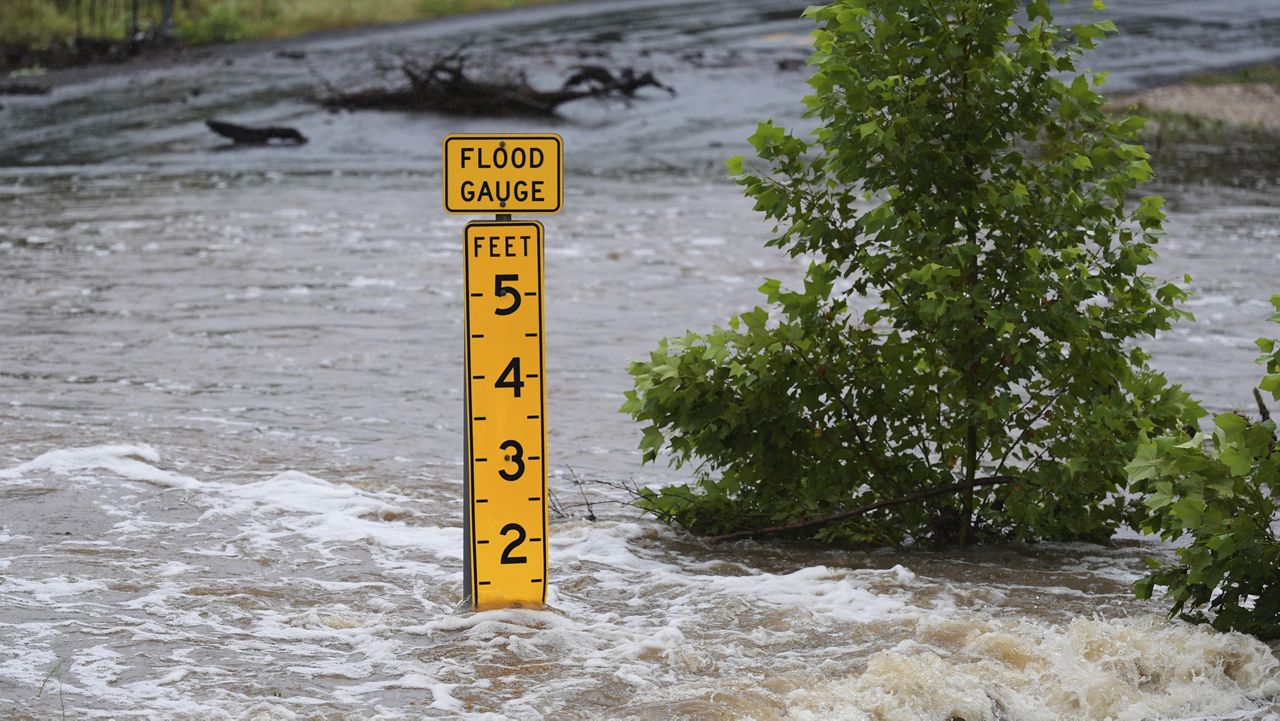A flood gauge marks the height of water flowing over a farm-to-market road near Kerrville, Texas, on Friday, July 4, 2025. (AP Photo/Eric Gay)