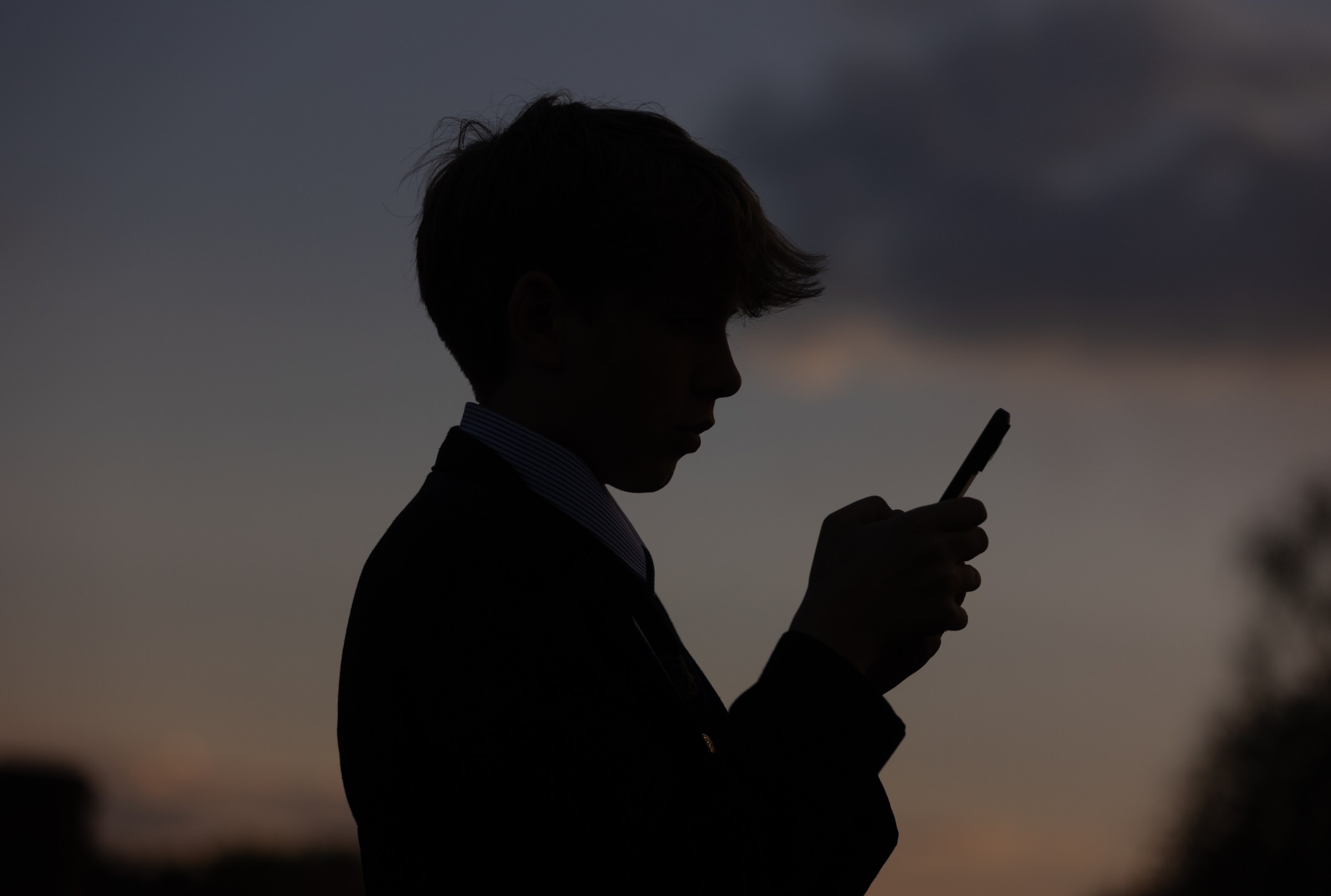 Shadow of a young person typing on their phone.