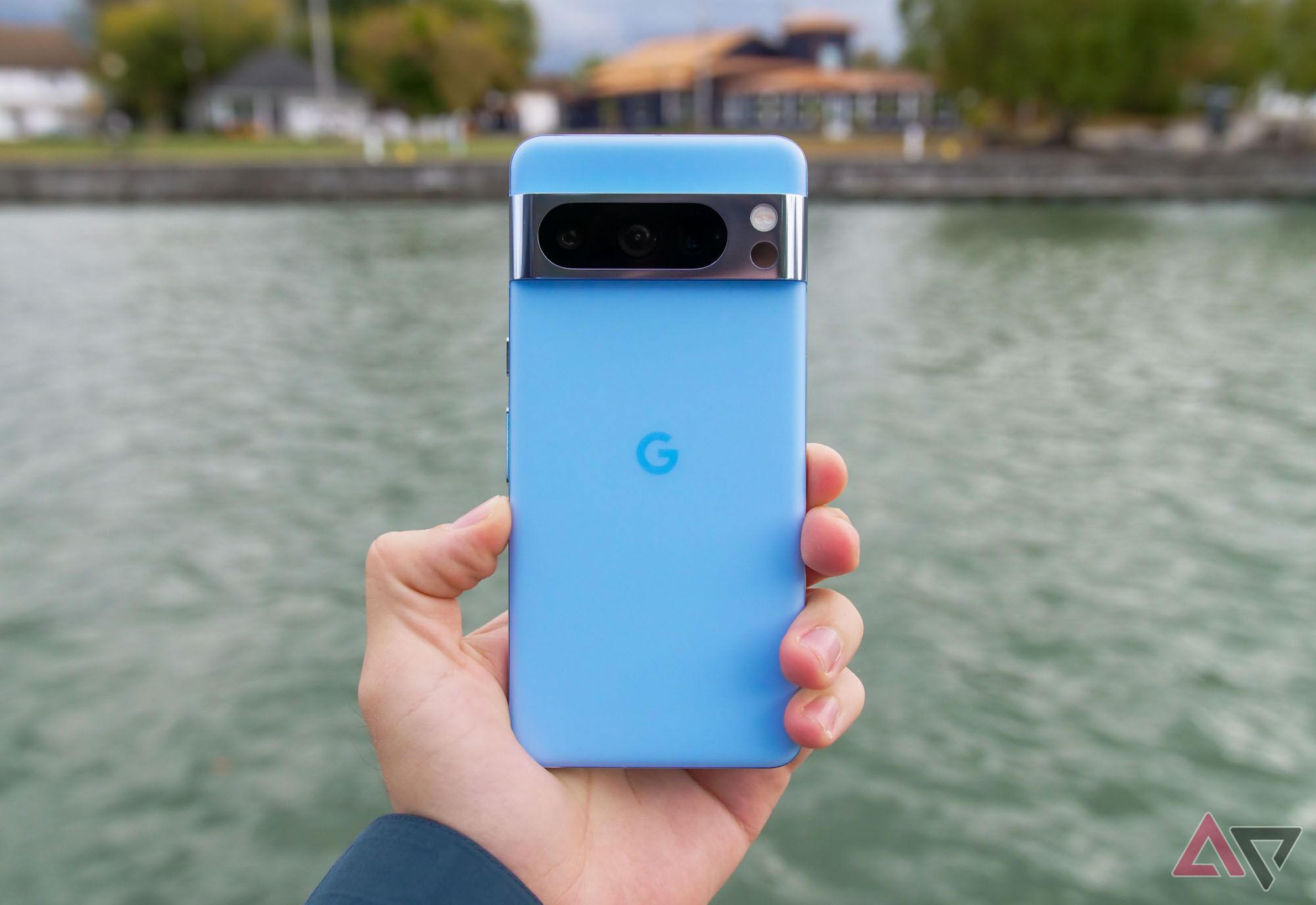The back of a Google Pixel 8 Pro with a lake in the background.