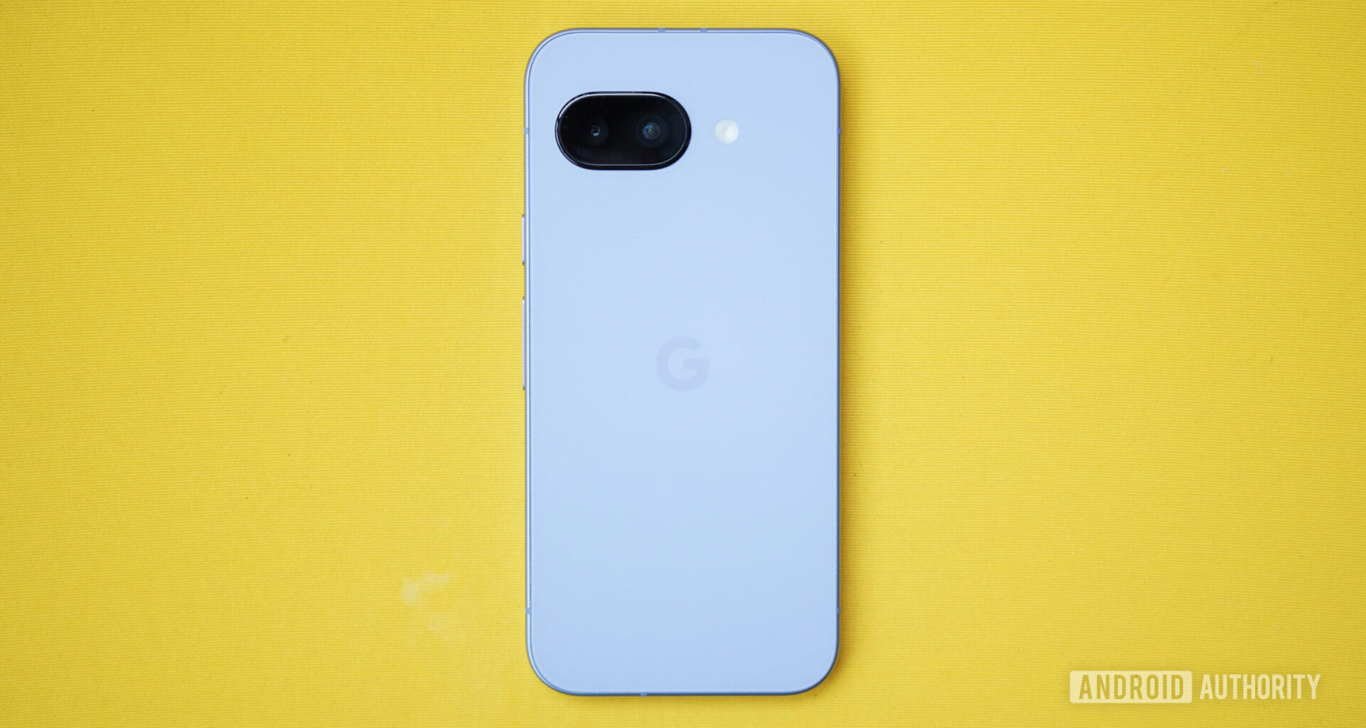 The Google Pixel 9a lying face-down on a yellow cushion.