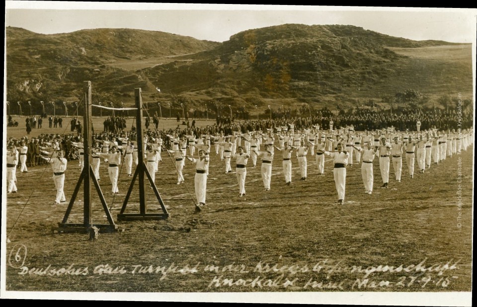 Photo of men in white uniforms performing calisthenics.