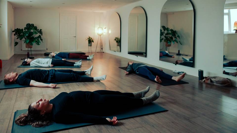 People lying on yoga mats during a fitness class.