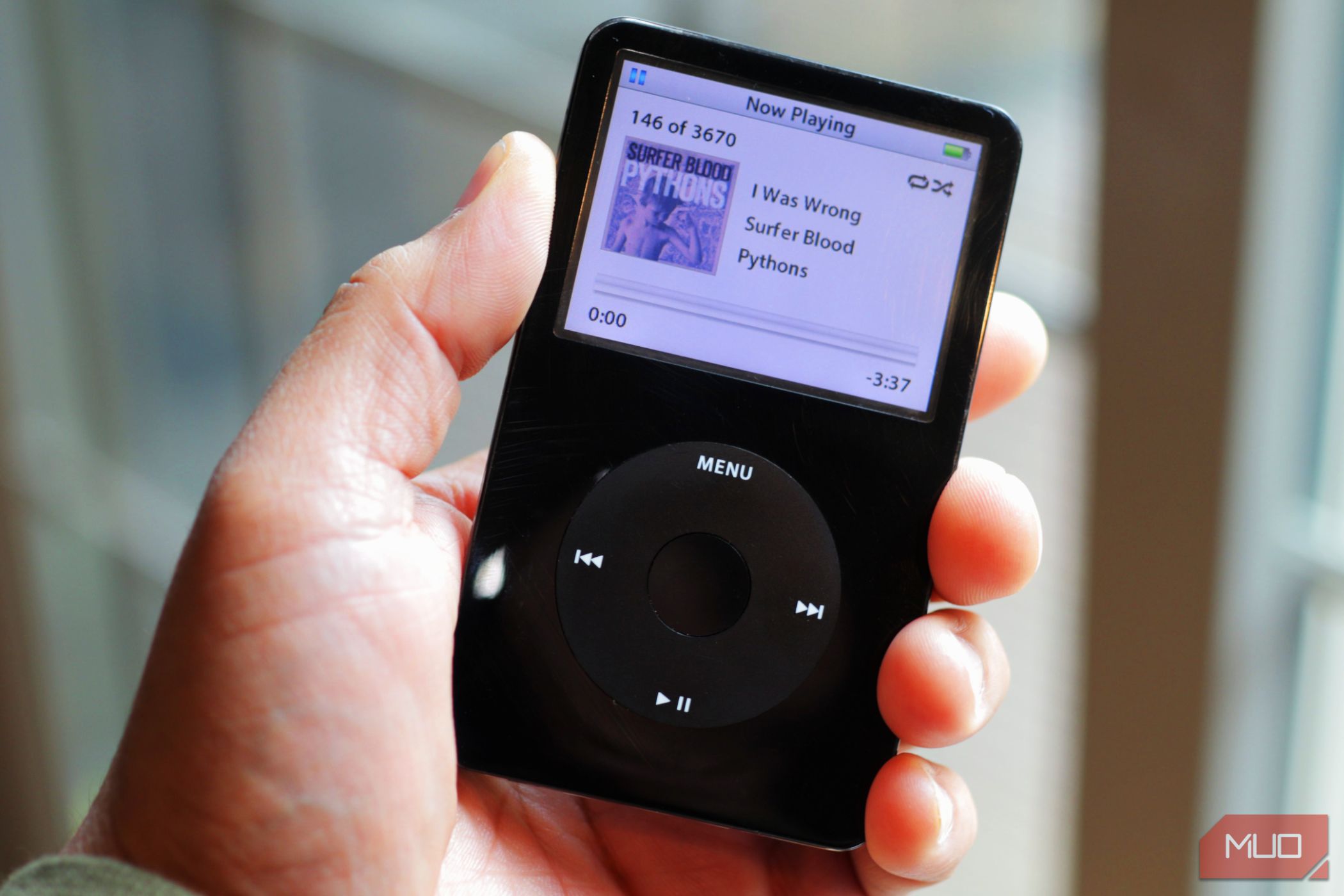 black iPod classic in hand near a window