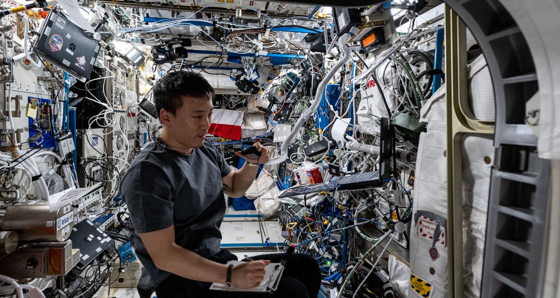 ASA astronaut and Expedition 73 Flight Engineer Jonny Kim conducts a ham radio session and takes notes inside the International Space Station's Columbus laboratory module.