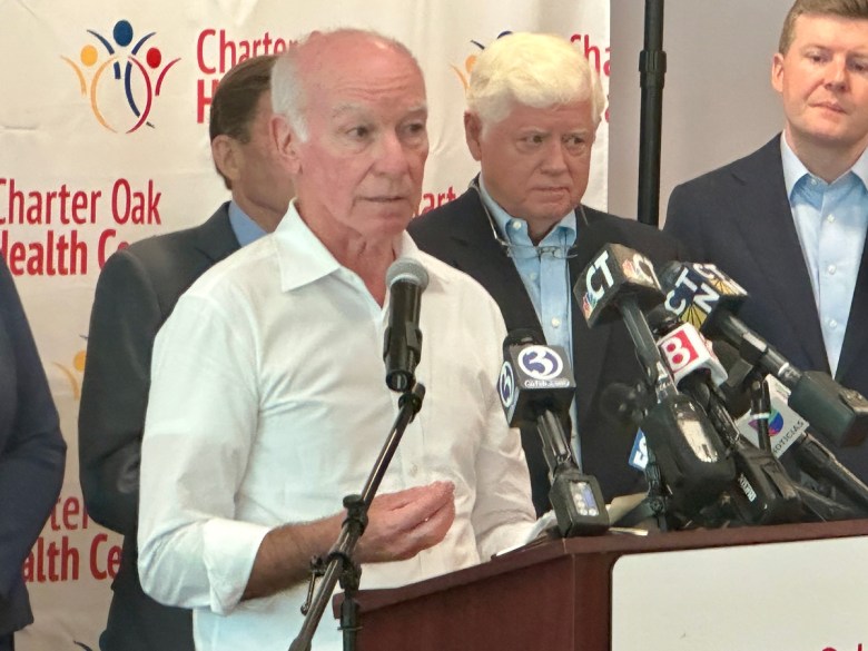Man in white shirt speaks into microphones