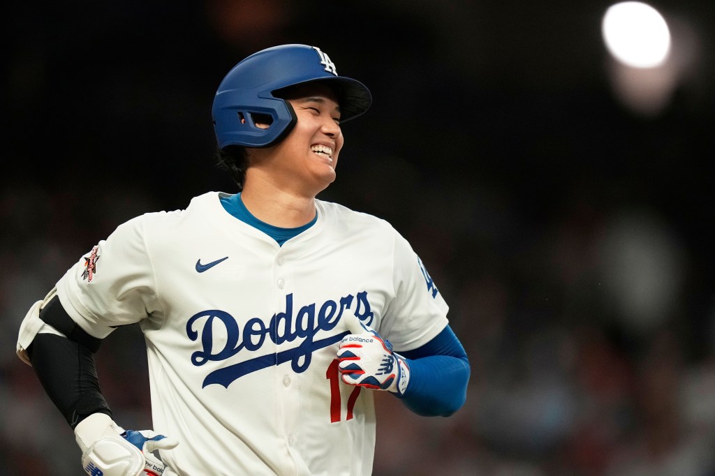 Shohei Ohtani smiles in a Los Angeles Dodgers uniform during a baseball game.