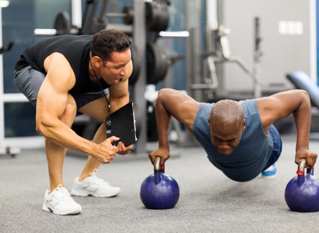 man doing pushups, working with personal trainer