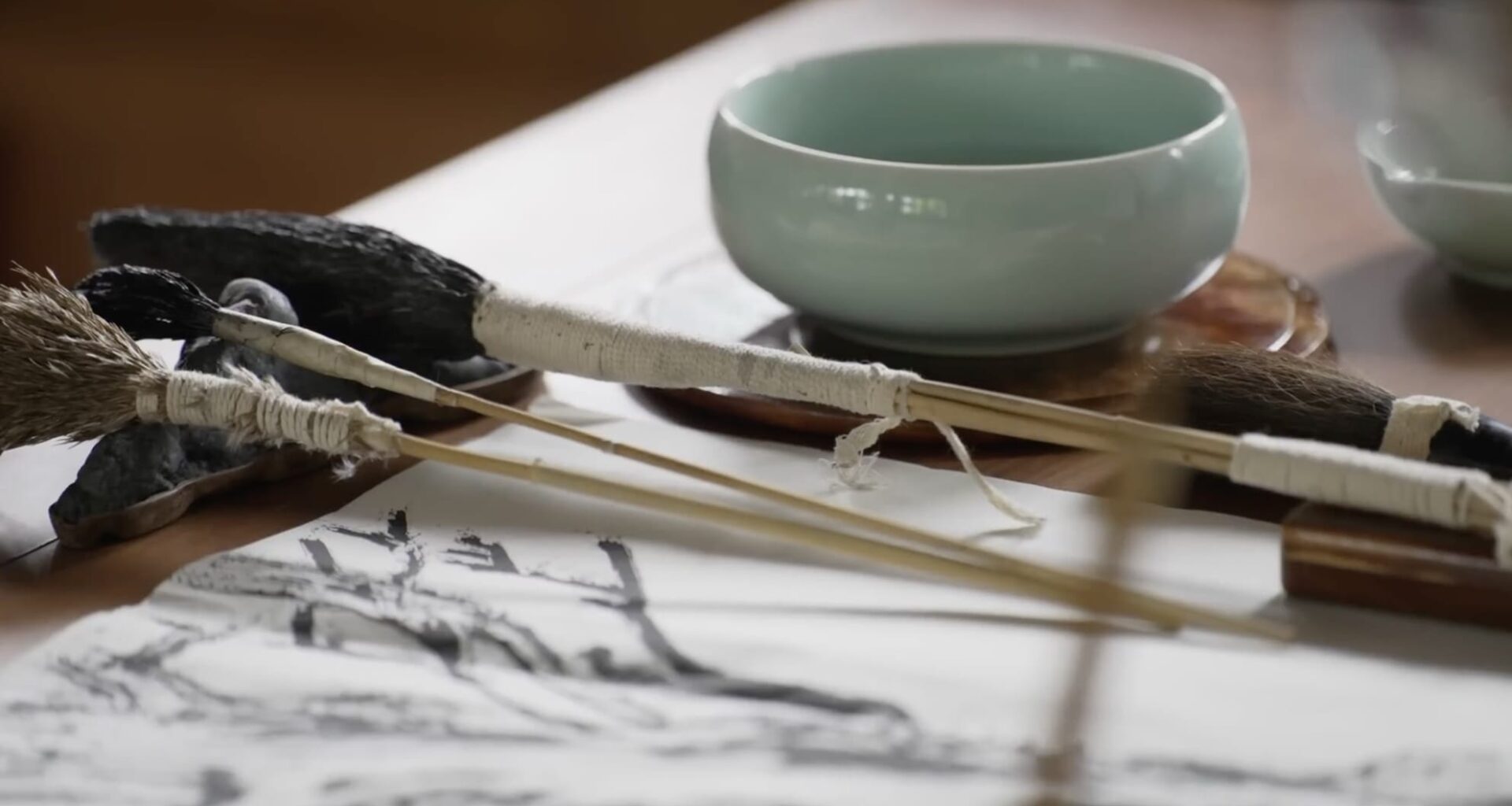 a still from a short documentary showing handmade brushes on a table with a bowl