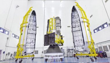 The NISAR satellite is seen with two halves of a payload fairing.