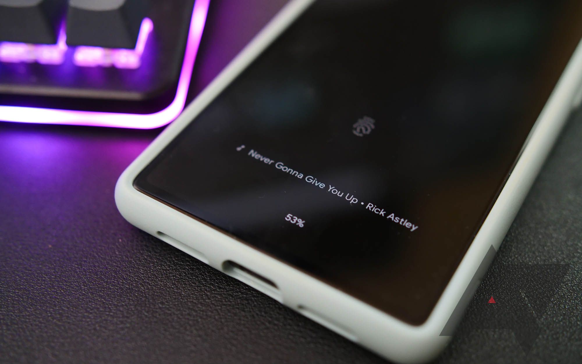 google pixel phone with now playing on lock screen next to purple lit keyboard