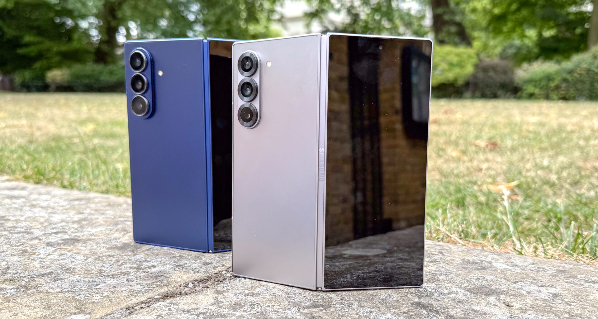 The Samsung Galaxy Z Fold 7 (blue, L) and Galaxy Z Fold 6 stood next to each other, partly folded