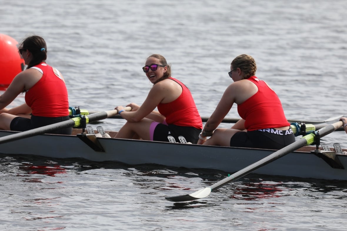 Close up of a team of women wearing red shirts in a row boat.