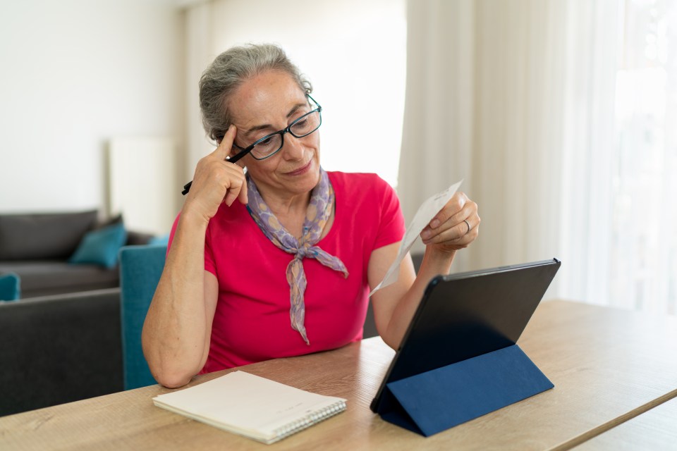Senior woman reviewing expenses on a tablet.