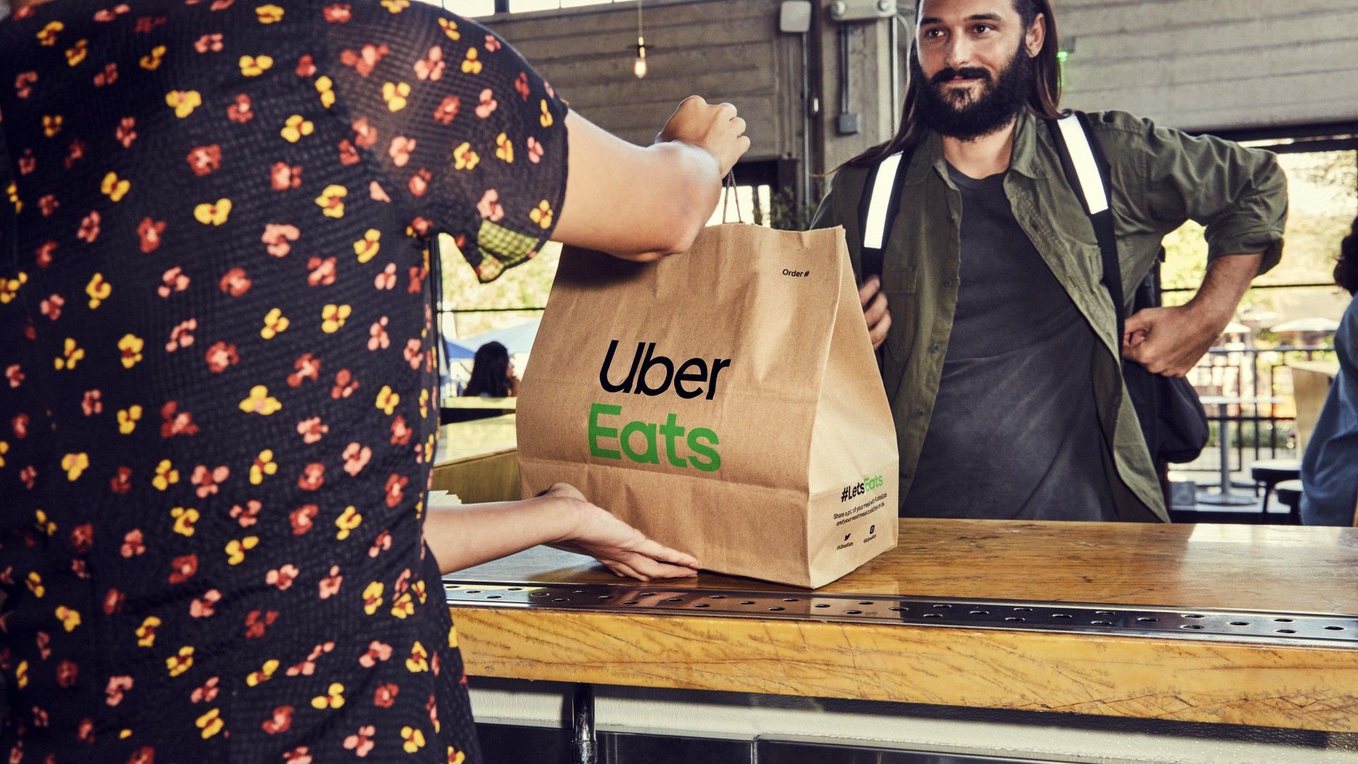 Someone picking up an Uber Eats bag full of food from a restaurant