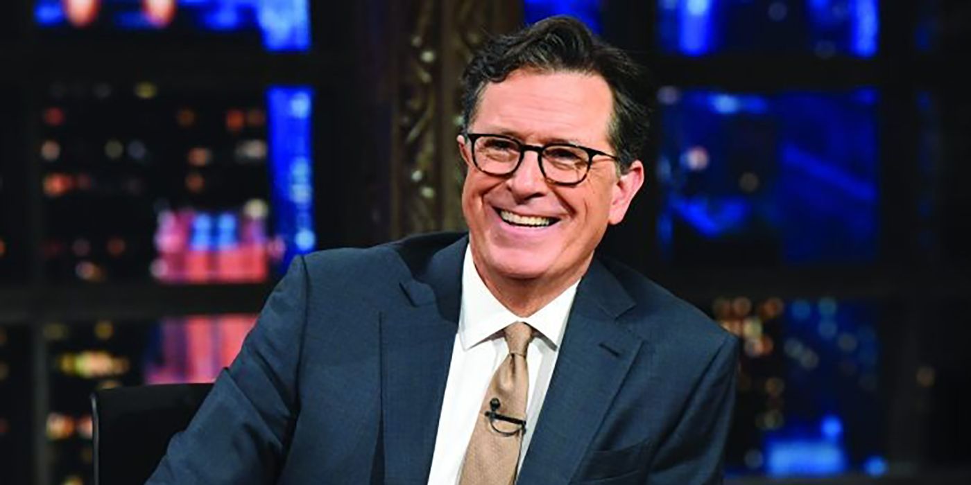 Stephen Colbert smiling behind his desk on The Late Show with Stephen Colbert.