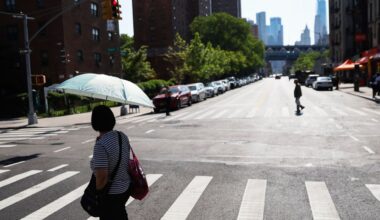 A pedestrian shields themselves from the sun as they cross the street on June 4, 2025, in New York. (AP Photo/Heather Khalifa)
