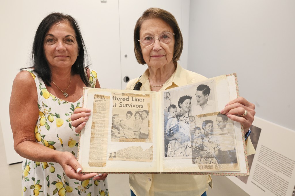 Two women display a scrapbook of photos and newspaper clippings about the Andrea Doria survivors.