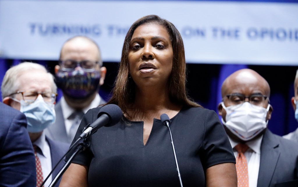 A woman speaking at a podium with other people wearing masks in the background.