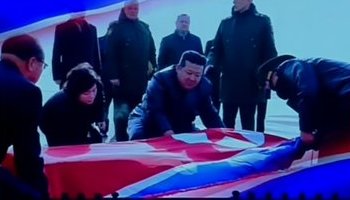 Kim Jong-un draping a flag over coffins of North Korean soldiers.