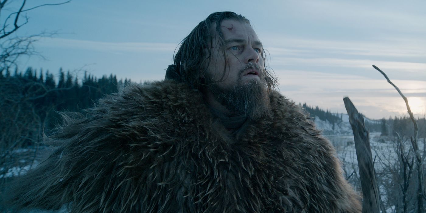 Hugh Glass looking up while standing in a snowy field in The Revenant.