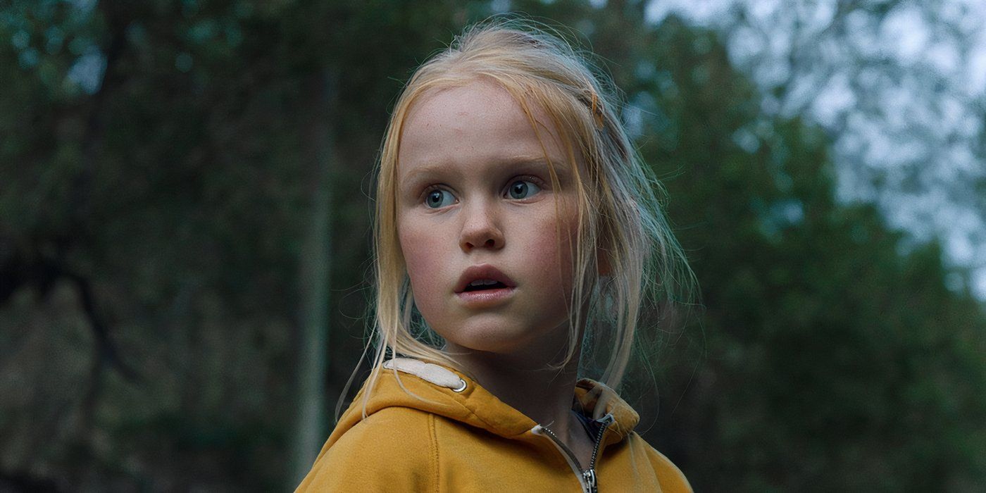 A young girl in a yellow sweater stares in fear in a forest in The Innocents.