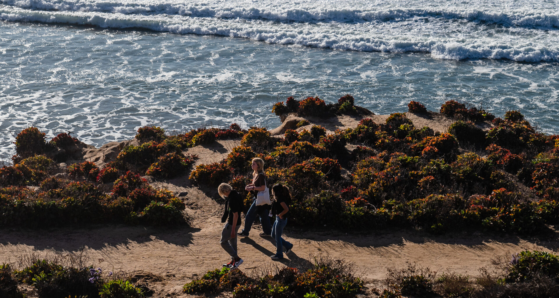 People walk near the ocean in Del Mar on Jan. 2, 2024.