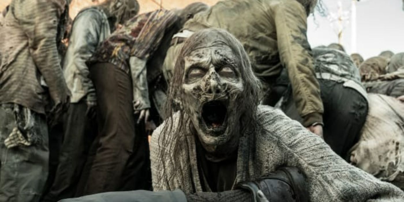 A growling zombie in The Walking Dead next to other zombies