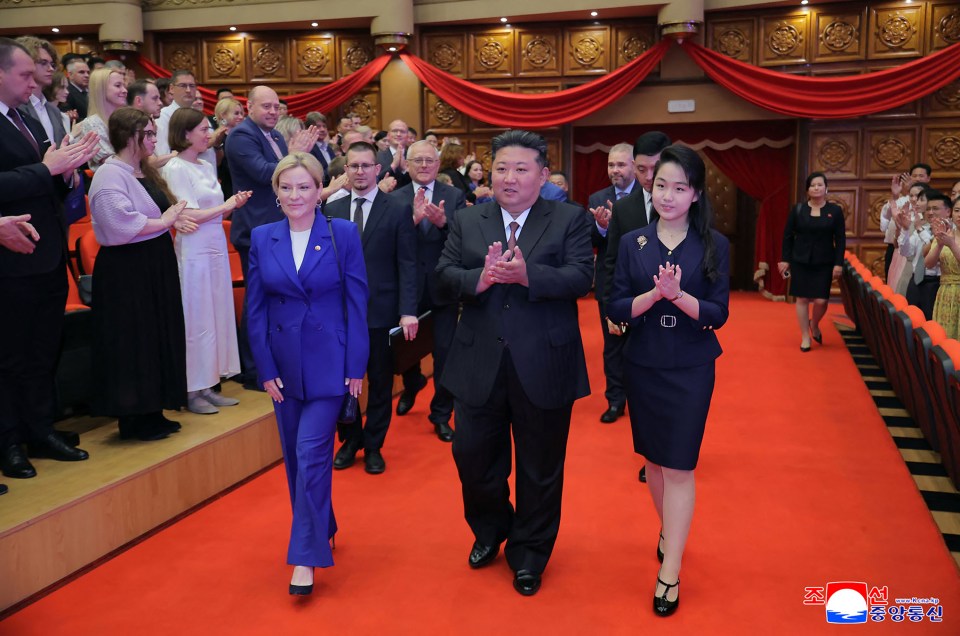 Kim Jong Un, his daughter, and Olga Lyubimova walking down a red carpet at a performance.