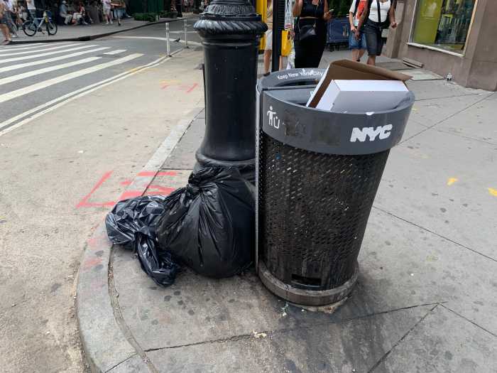 a public garbage can on a street corner