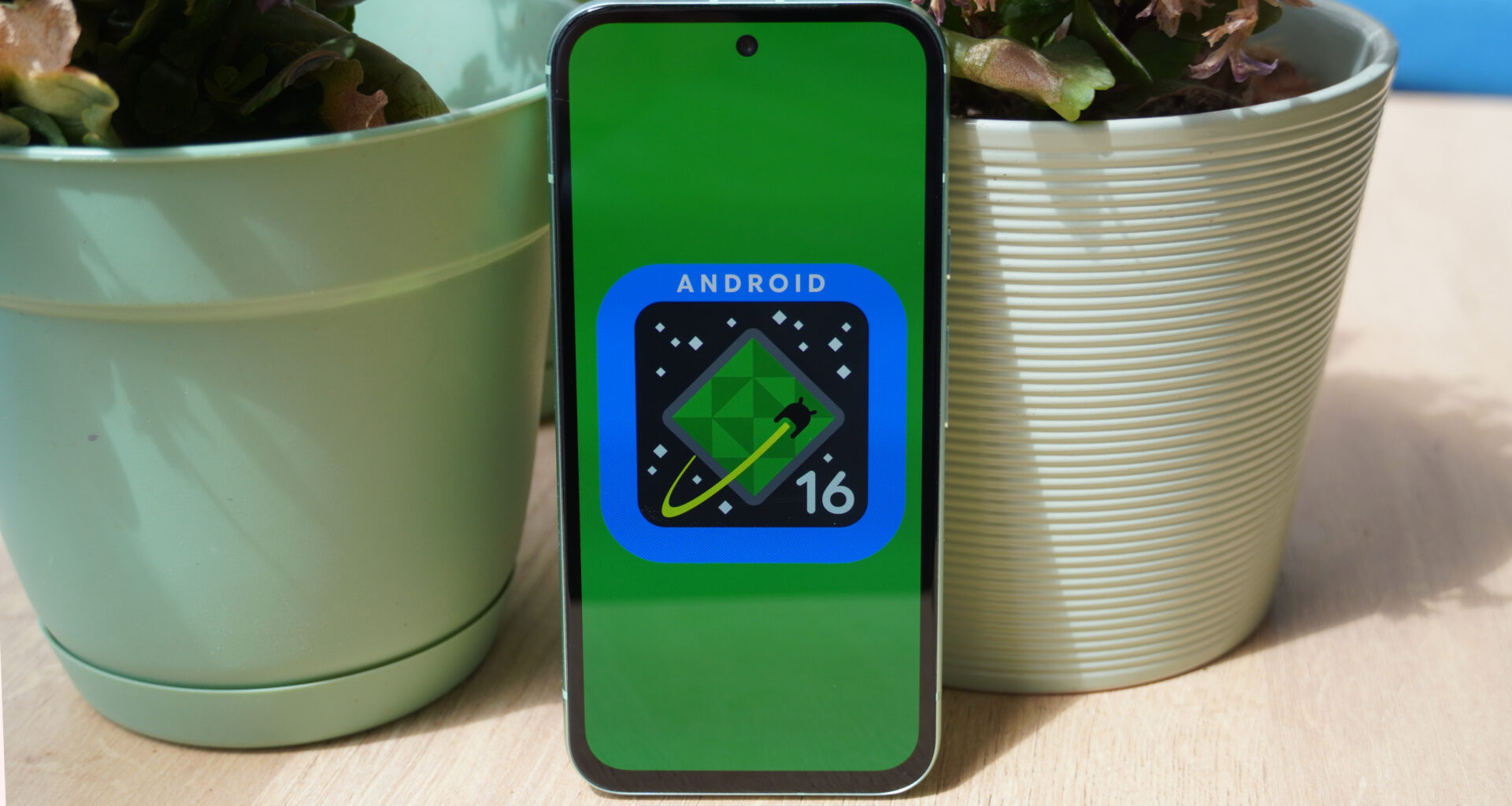 The Android 16 logo on a Google Pixel 8a outdoors.