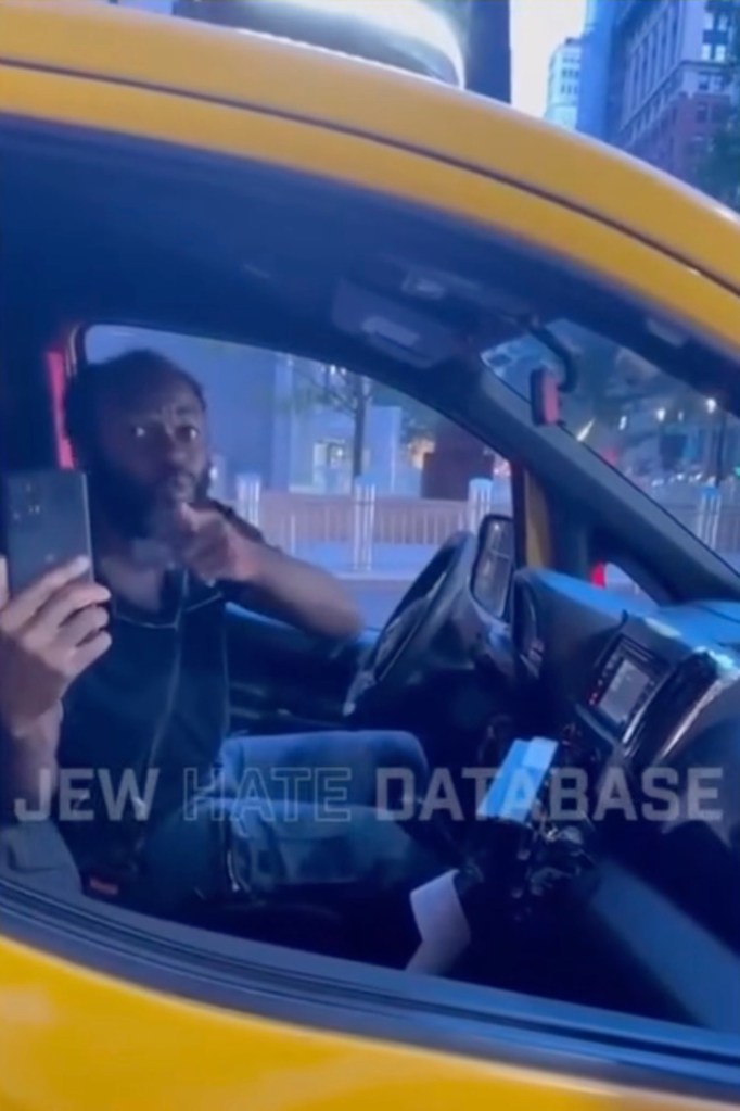 the cabbie holding up a cell phone and talking to someone at the window of the vehicle