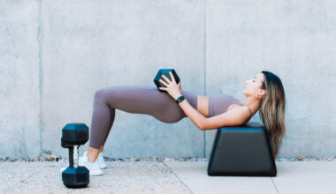 A woman performing a glute bridge with dumbbells