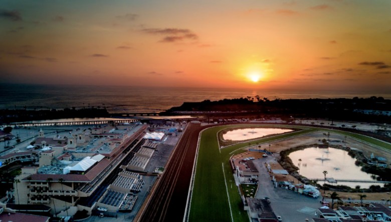 The sun setting over the ocean with a horse racing venue in the foreground.