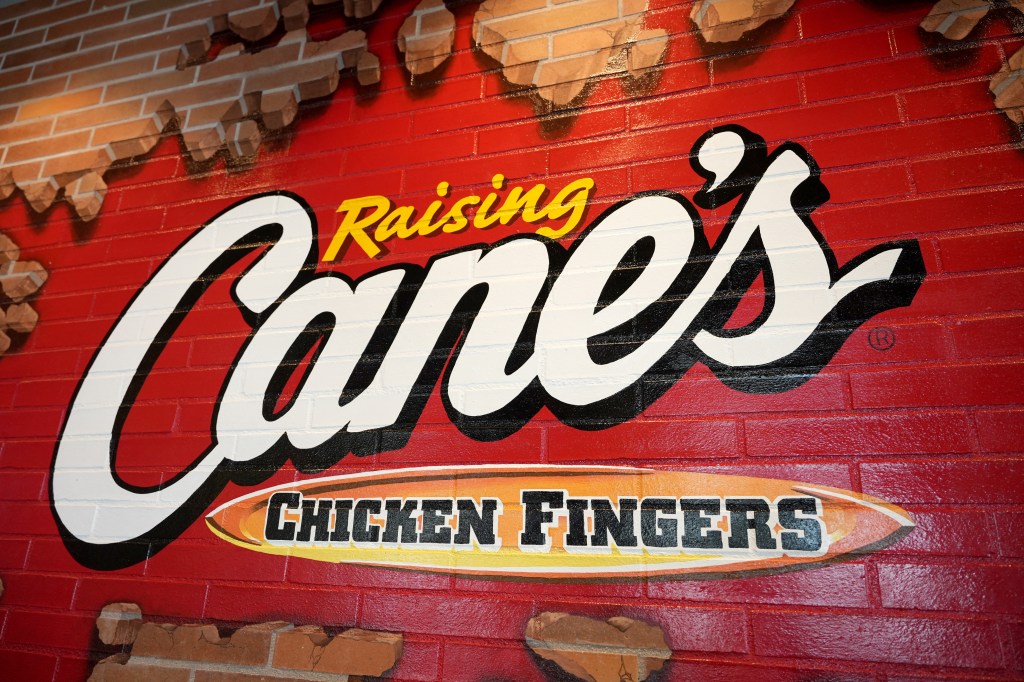 Raising Cane's Chicken Fingers logo on a brick wall.