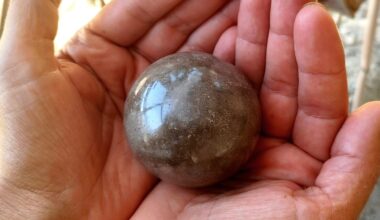 Hand holding shiny mud ball.