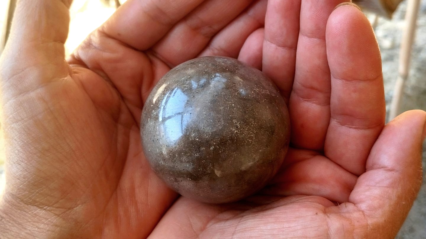Hand holding shiny mud ball.